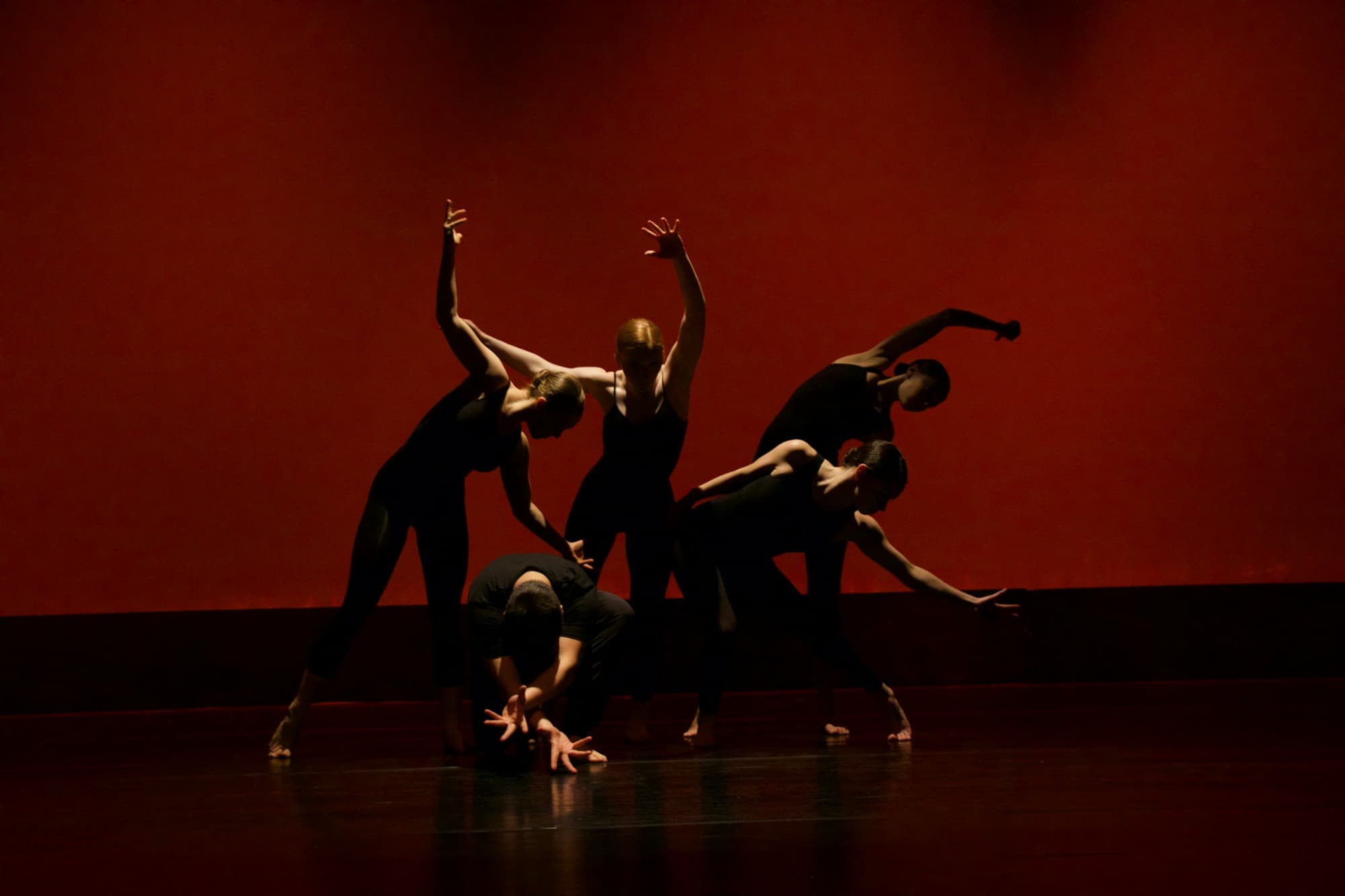 Groupe de danseurs sur scène devant un fond rouge