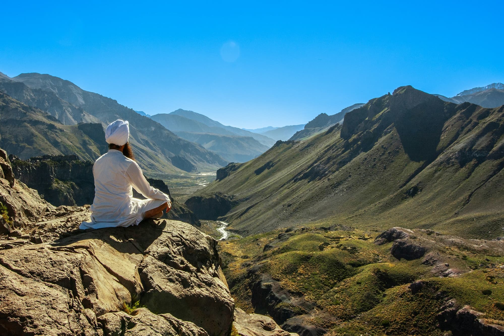 Pratiquant de Kundalini Yoga vêtu de blanc, en méditation face aux montagnes